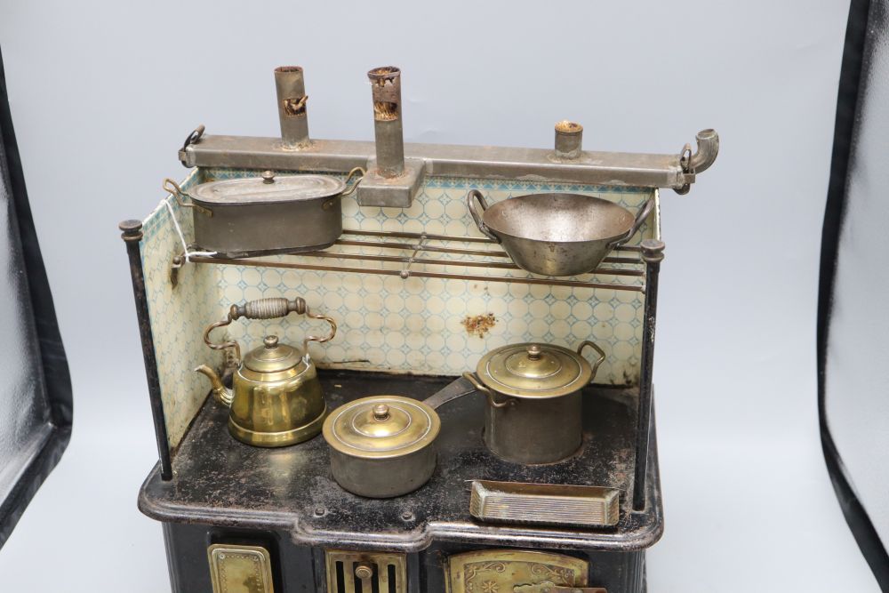 A German tin plate miniature stove, with cooking utensils, height 39cm